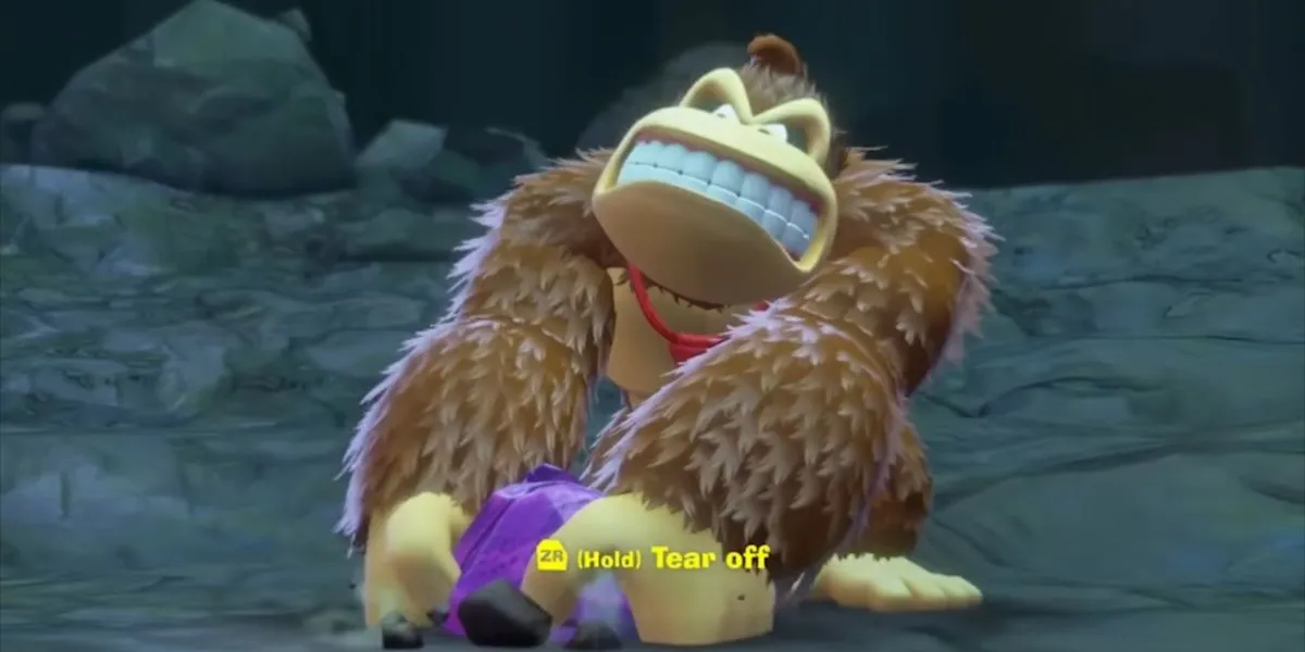 Donkey Kong đang xé một mảnh đất lên khỏi mặt đất trong Donkey Kong Bananza, biểu thị kỹ năng Tear Off Chunks đa dụng để tạo ra lợi thế trong di chuyển và chiến đấu.